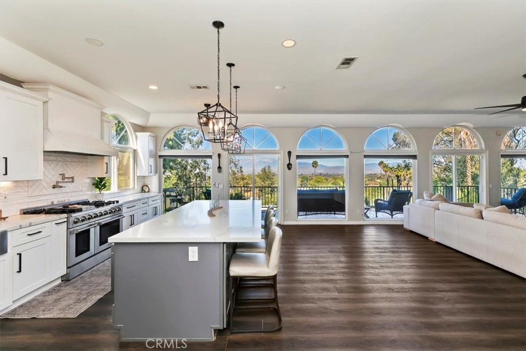 1619 Gratton Street Riverside, CA 92504 - Photo 22 of 62 a large kitchen with stainless steel appliances granite countertop a stove a refrigerator a kitchen island a couches and a dining table with wooden floor