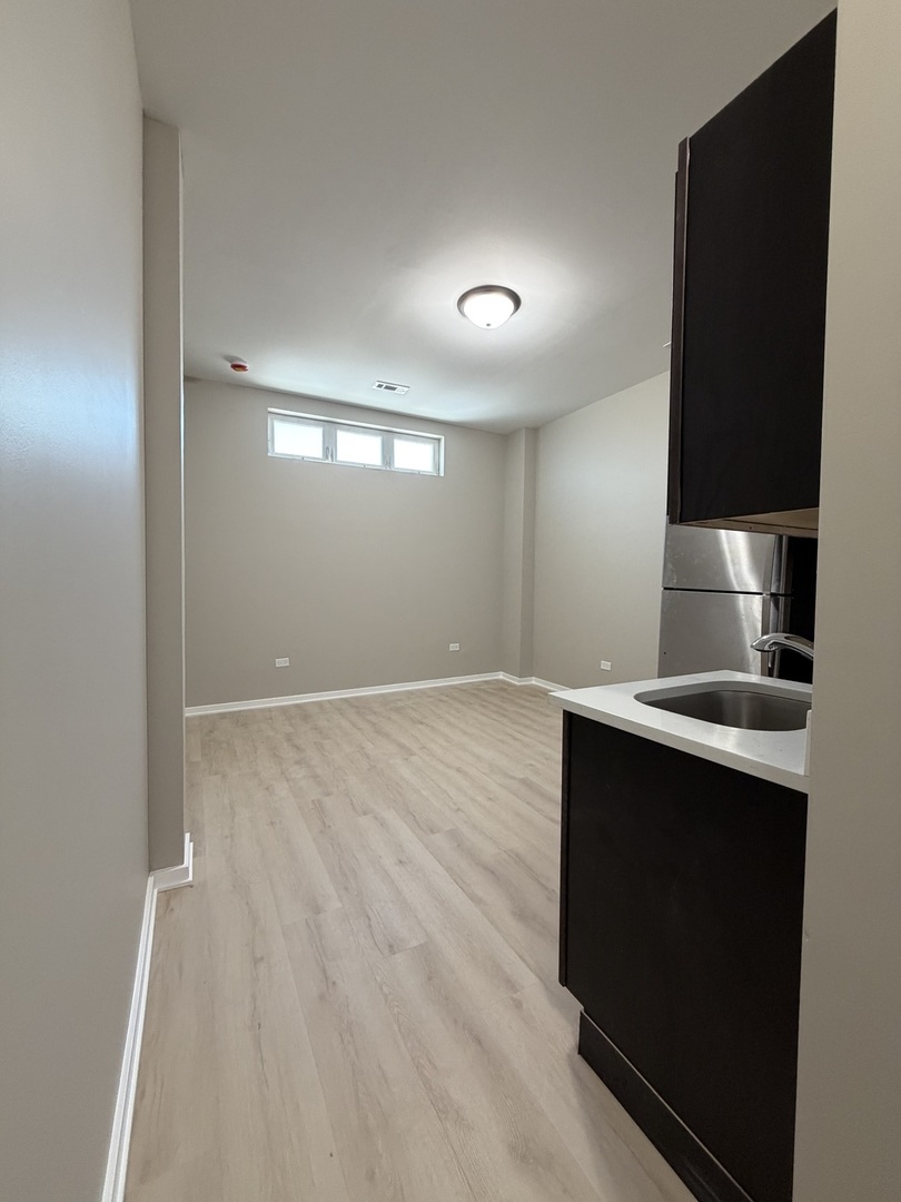 24 North Pulaski Road, Unit 1F Chicago, IL 60624 - Photo 3 of 10 a kitchen with kitchen island a sink wooden floor and black appliances