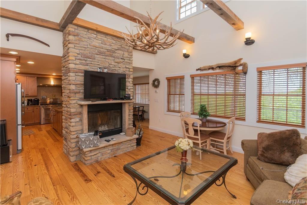 669 Mountain Road Bloomingburg, NY 12721 - Photo 14 of 36 Living room featuring a high ceiling, light wood finished floors, a fireplace, and suspended lighting