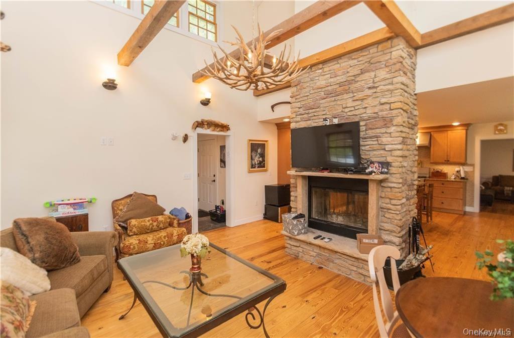 669 Mountain Road Bloomingburg, NY 12721 - Photo 15 of 36 Living room with a high ceiling, light wood finished floors, a stone fireplace, and hanging lights