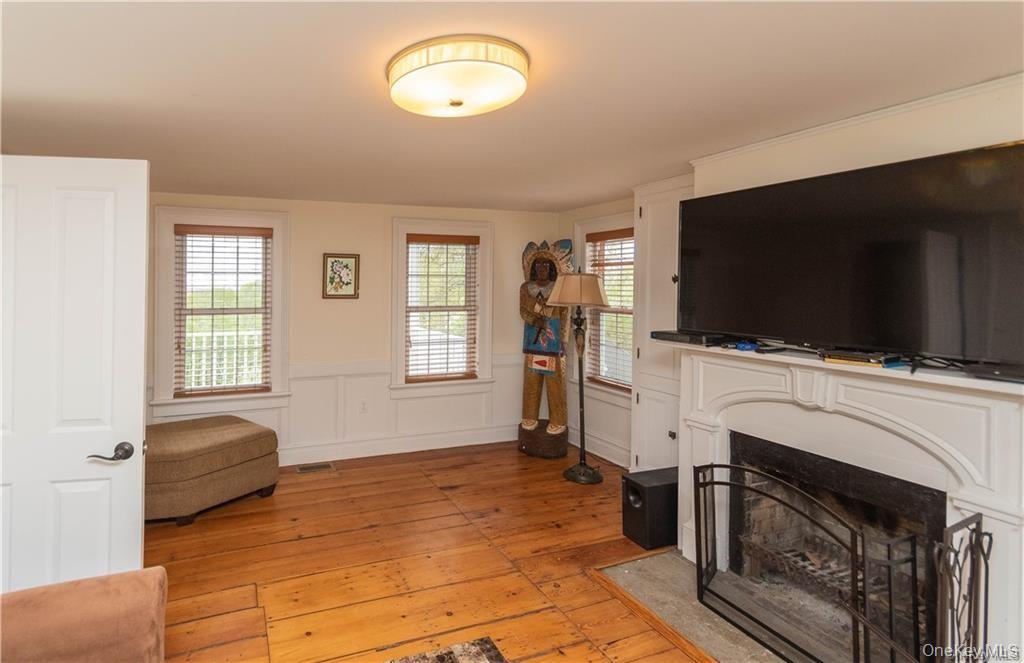 669 Mountain Road Bloomingburg, NY 12721 - Photo 17 of 36 Living area featuring light wood-style flooring, a fireplace with flush hearth, a wainscoted wall, and a decorative wall