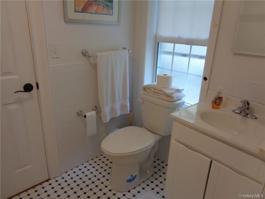 669 Mountain Road Bloomingburg, NY 12721 - Photo 26 of 36 Half bathroom featuring tile walls, vanity, light tile patterned floors, and a wainscoted wall