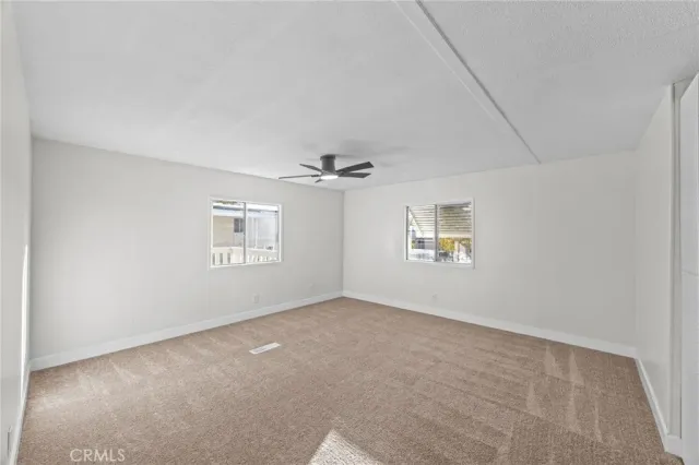 an empty room with windows and ceiling fan