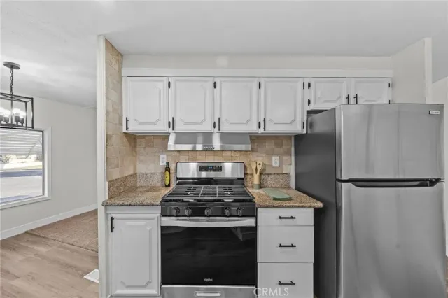 a kitchen with refrigerator a stove and white cabinets