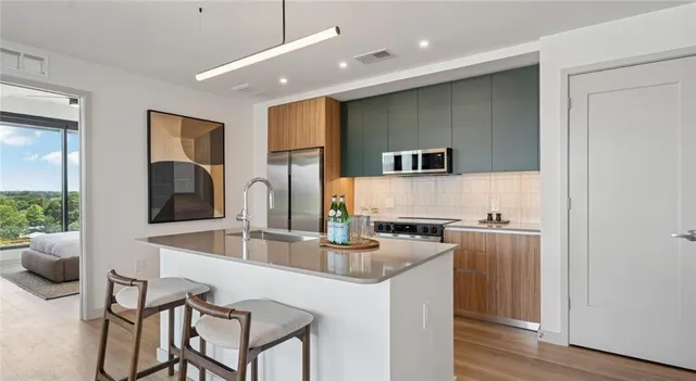 a kitchen with kitchen island granite countertop a sink and a refrigerator
