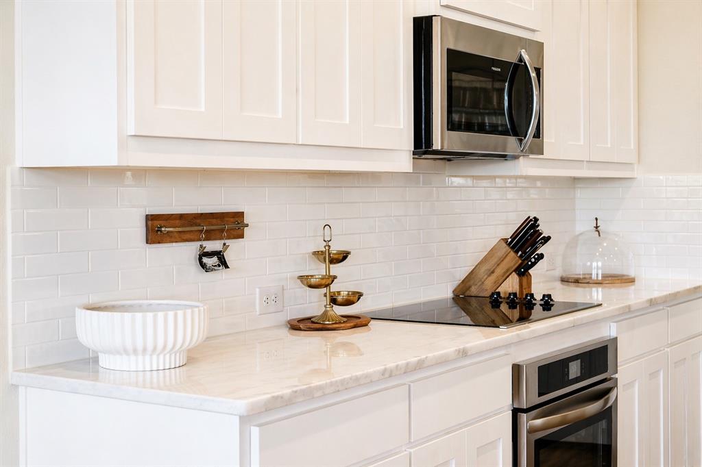1530 County Road 200 Valley View, TX 76272 - Photo 12 of 34 Modern kitchen featuring white shaker cabinetry, light-toned countertops, a white subway tile backsplash, stainless steel microwave, and a flush-mounted cooktop