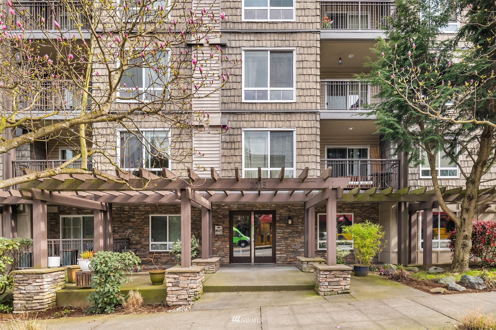 3015 Southwest Avalon Way, Unit 106 Seattle, WA 98126 - Photo 2 of 20 a front view of a building with lots of windows and plants