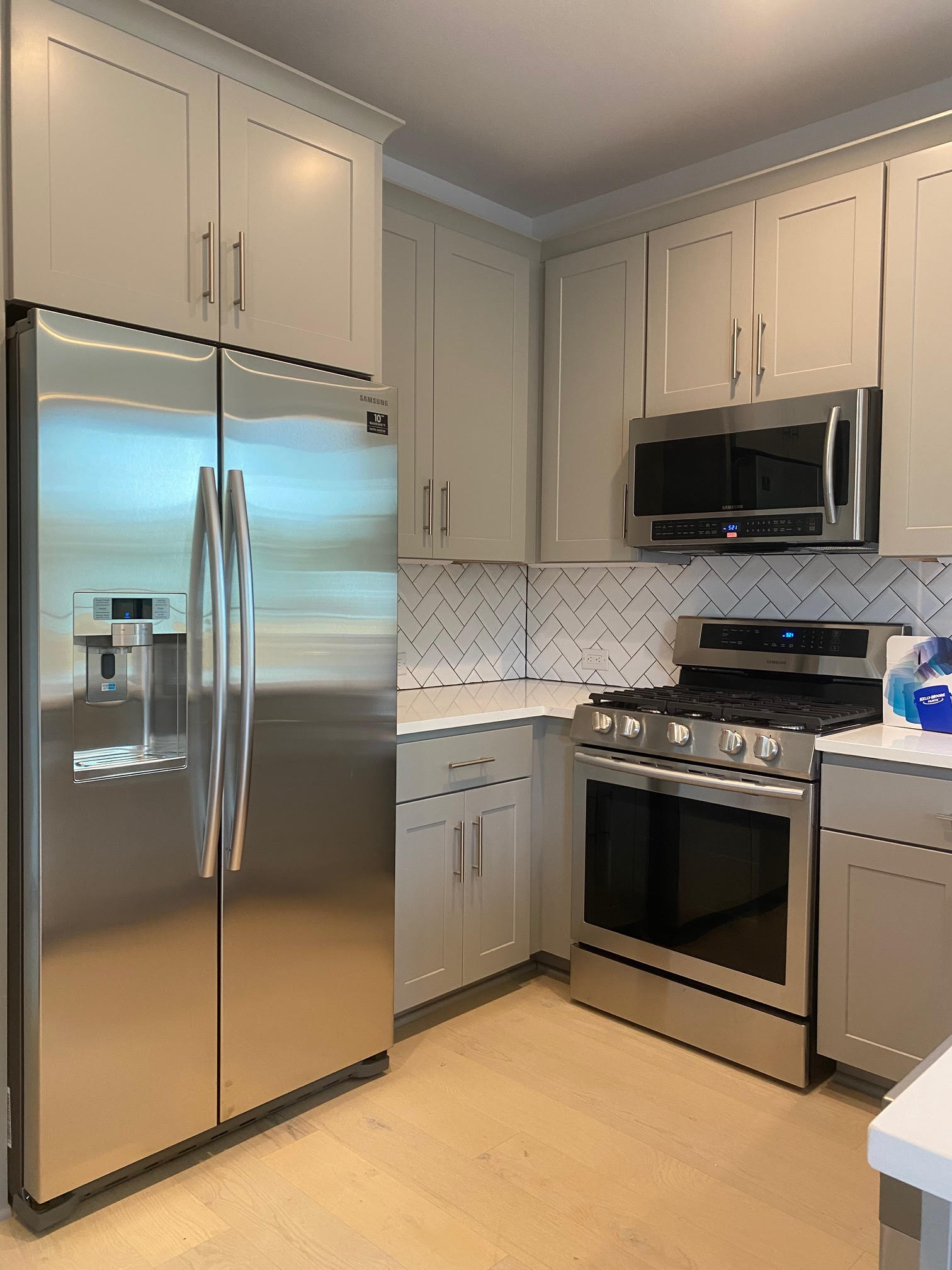 6920 Bethune Avenue, Unit 3 Austin, TX 78752 - Photo 6 of 32 Kitchen featuring appliances with stainless steel finishes, gray cabinetry, light wood-style floors, tasteful backsplash, and light stone countertops