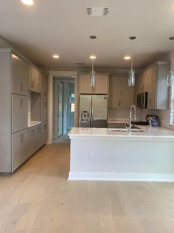 a view of kitchen with stainless steel appliances granite countertop refrigerator sink and white cabinets