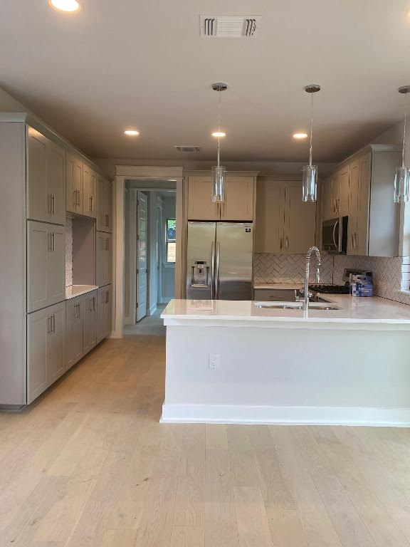 6920 Bethune Avenue, Unit 3 Austin, TX 78752 - Photo 7 of 32 Kitchen with stainless steel appliances, decorative light fixtures, a peninsula, light wood-style floors, and gray cabinetry