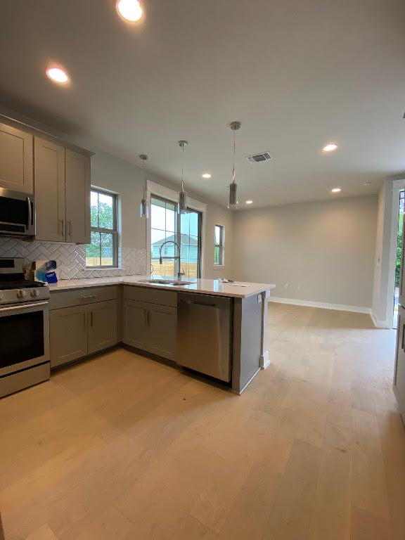 6920 Bethune Avenue, Unit 3 Austin, TX 78752 - Photo 9 of 32 Kitchen with stainless steel appliances, pendant lighting, light wood-style flooring, tasteful backsplash, and recessed lighting
