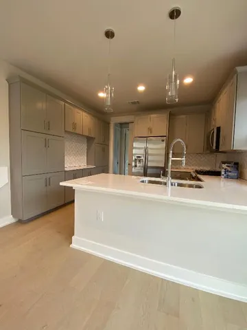 a large kitchen with a large counter top a sink stainless steel appliances and cabinets