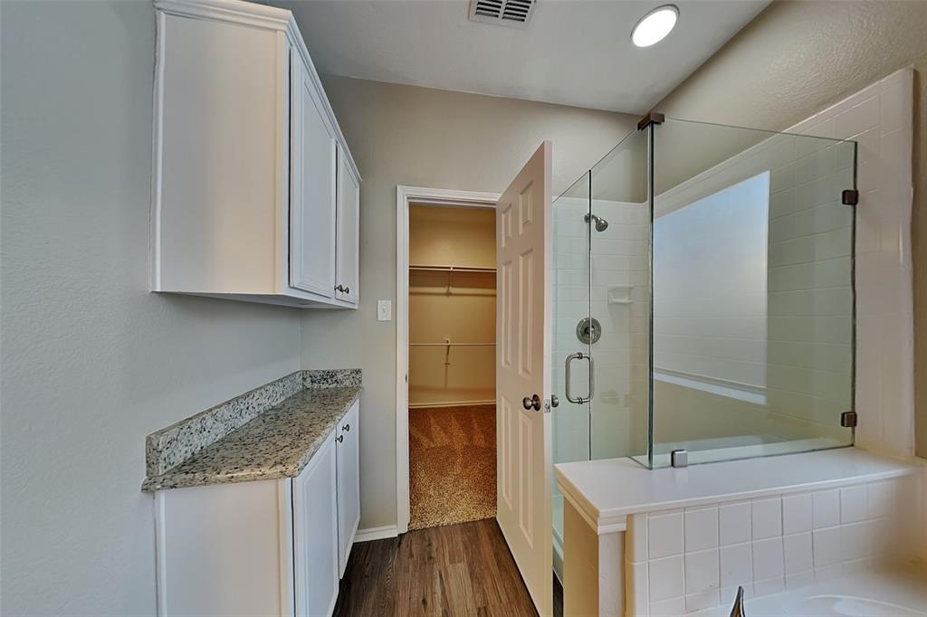 1202 Dove Brook Drive Allen, TX 75002 - Photo 11 of 23 Bathroom with a spacious closet, dark wood-style flooring, a shower stall, vanity, and a garden tub
