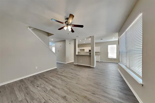 a view of an empty room with a kitchen and wooden floor