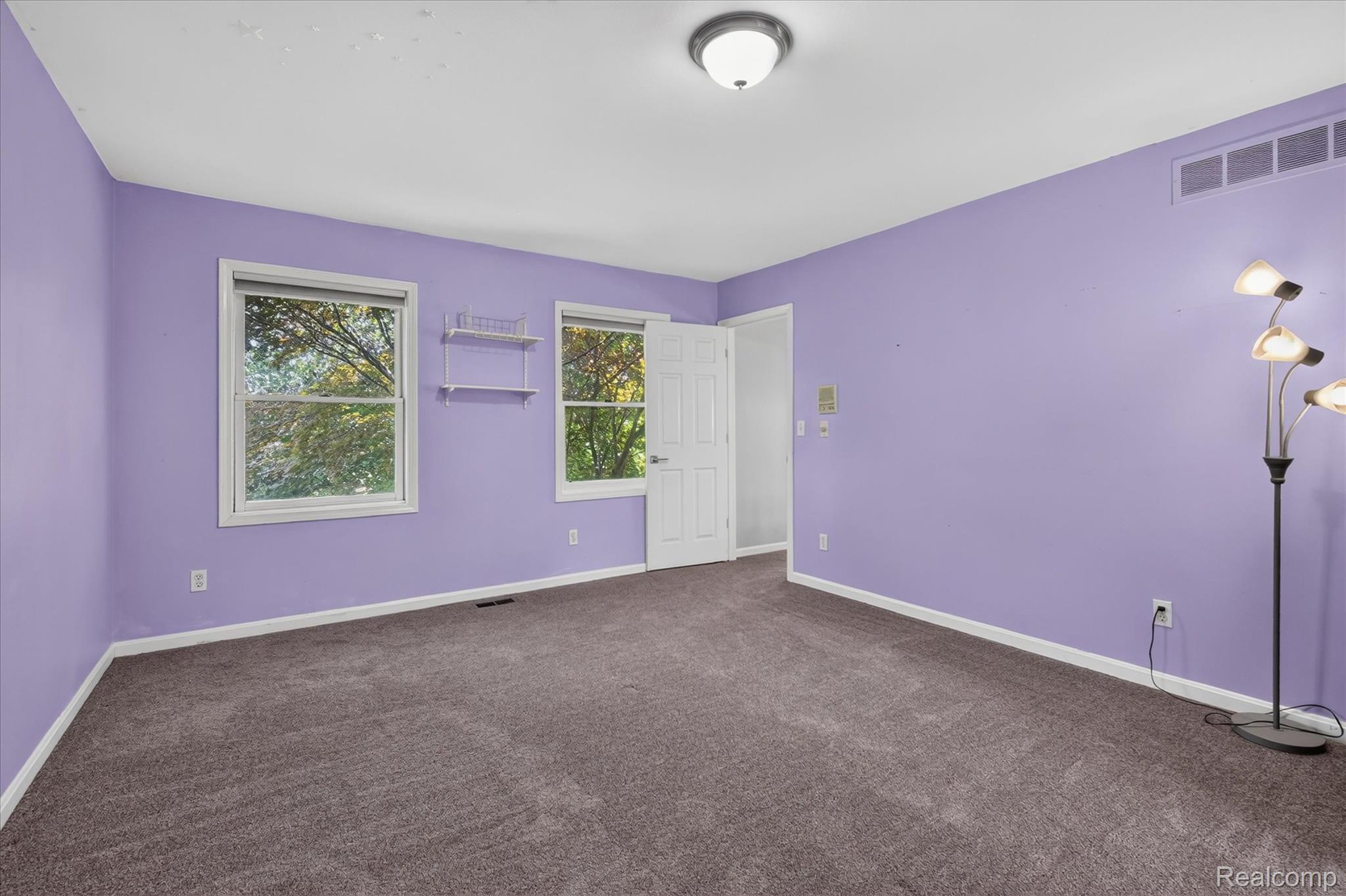 8114 Chilson Road Pinckney, MI 48169 - Photo 15 of 32 Spacious room featuring broadloom carpet flooring, two windows with exterior views, white trim throughout, and a flush mount ceiling light fixture