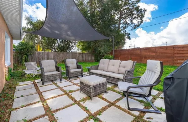 a view of a patio with table and chairs under an umbrella with a garden