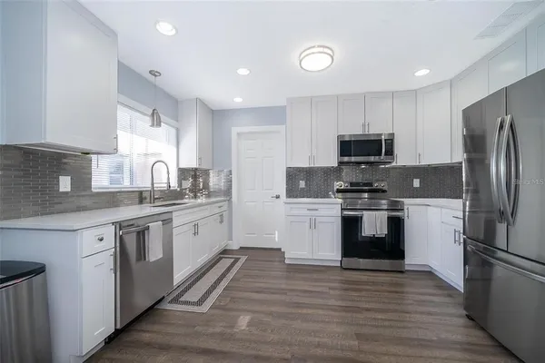 a kitchen with a sink a refrigerator and white cabinets