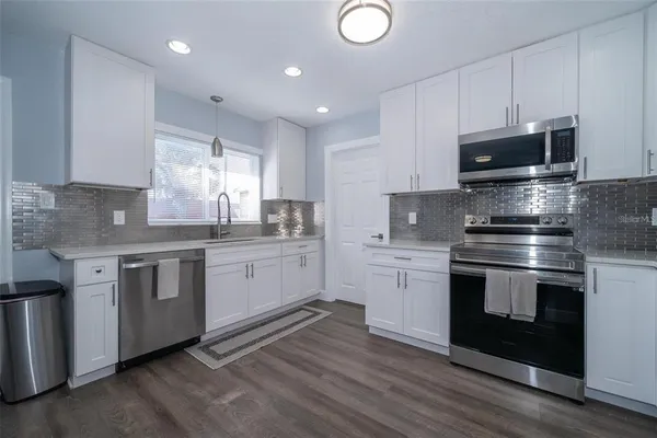 a kitchen with stainless steel appliances granite countertop a stove a sink and a microwave