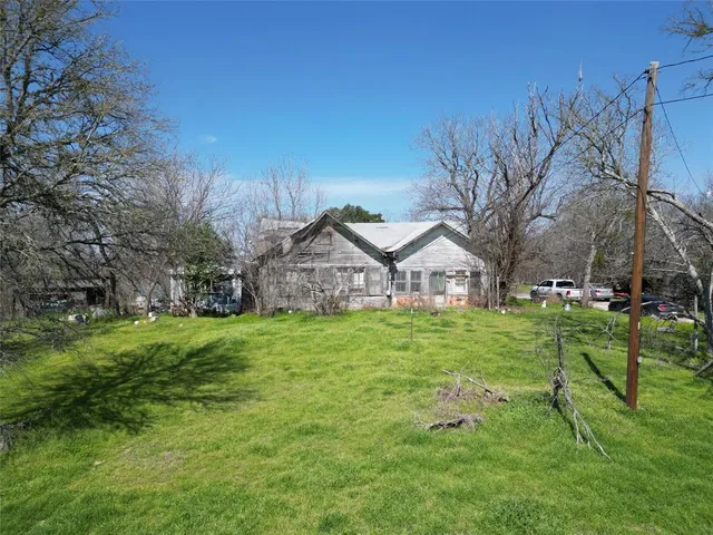 a view of a big house with a big yard and large trees