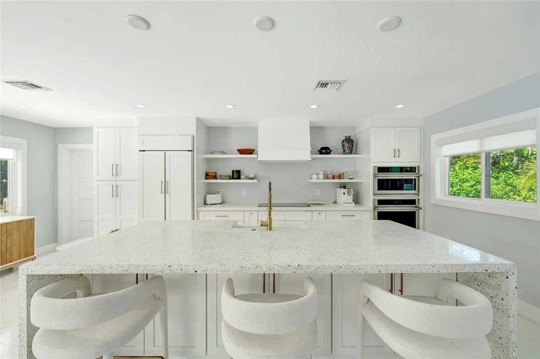 406 Indian Lilac Road Vero Beach, FL 32963 - Photo 5 of 36 a kitchen with stainless steel appliances kitchen island granite countertop a table and chairs