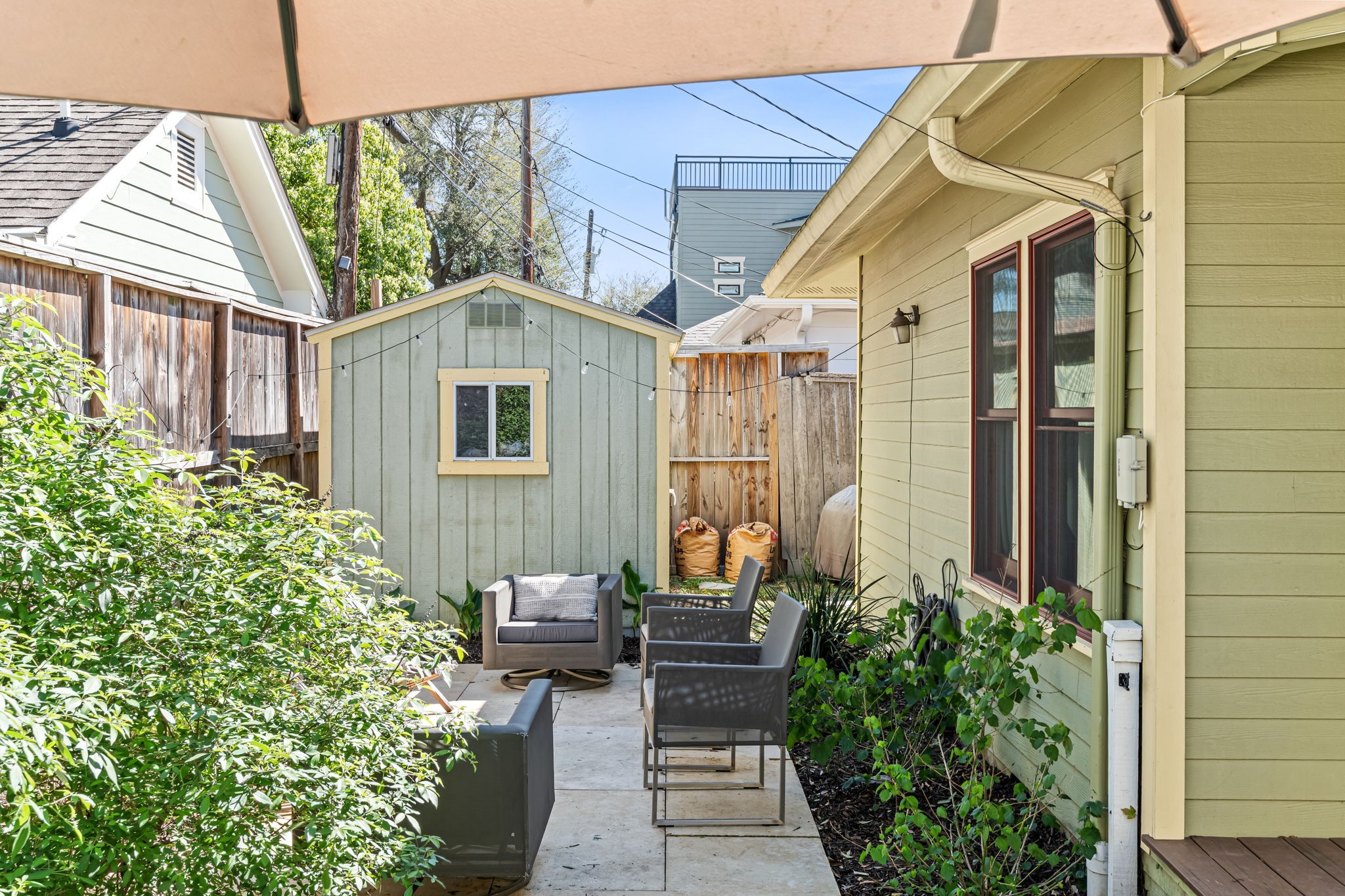 805 Ralfallen Street Houston, TX 77008 - Photo 26 of 32 Cozy backyard seating area surrounded by greenery, featuring a small patio space perfect for relaxing and a charming storage shed tucked at the rear of the yard.