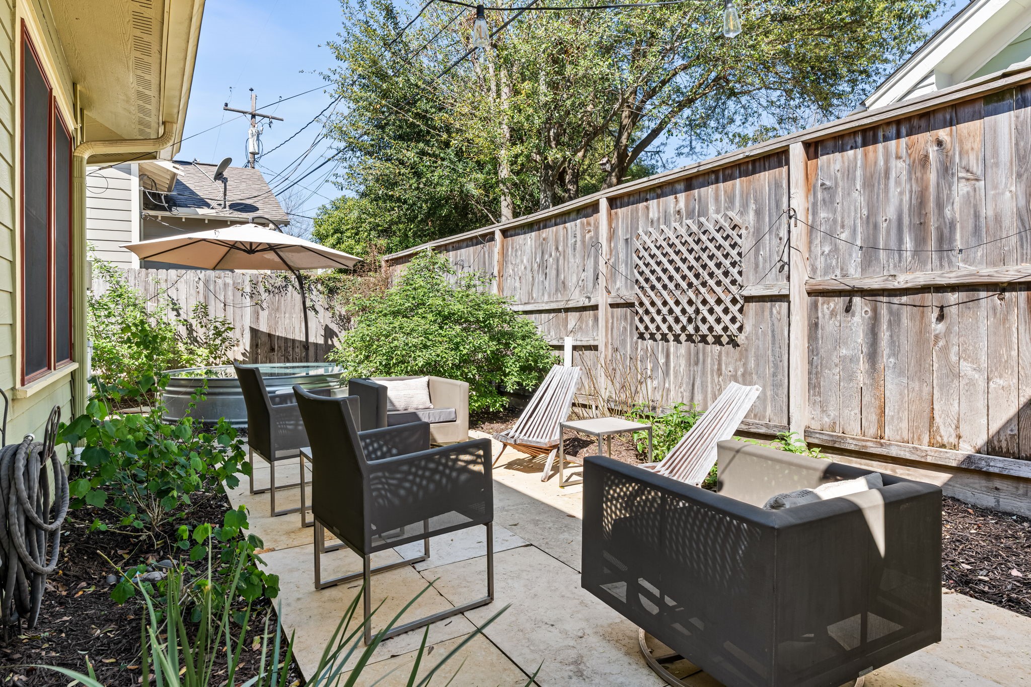 805 Ralfallen Street Houston, TX 77008 - Photo 27 of 32 Intimate patio lounge surrounded by mature landscaping, creating a relaxed outdoor setting ideal for gathering, unwinding, and enjoying the private backyard atmosphere.