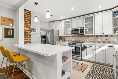 a kitchen that has a lot of white cabinets and stainless steel appliances