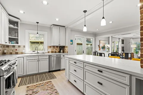 a large kitchen with granite countertop a large white cabinets and white appliances
