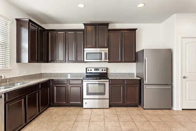 a kitchen with stainless steel appliances granite countertop a sink refrigerator and microwave