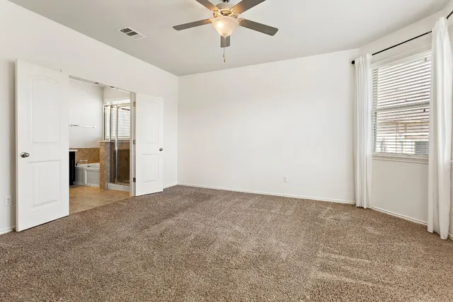 an empty room with windows and fan