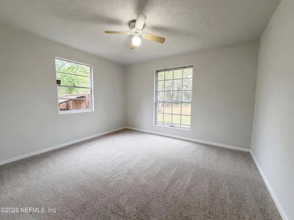 an empty room with windows and fan