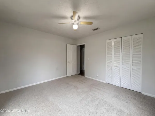 a view of an empty room with a chandelier fan