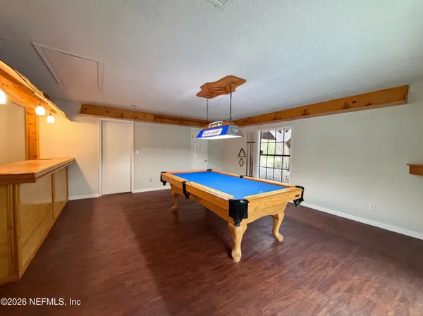a room with pool table windows and wooden floor
