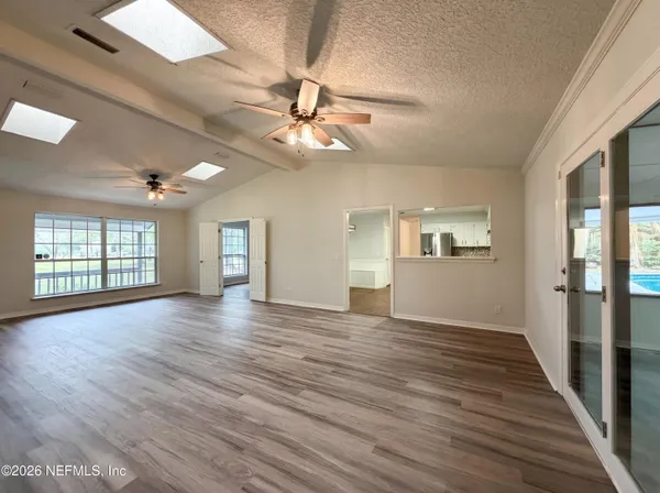 a view of an empty room with window and wooden floor