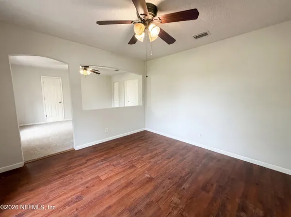 an empty room with wooden floor fan and windows
