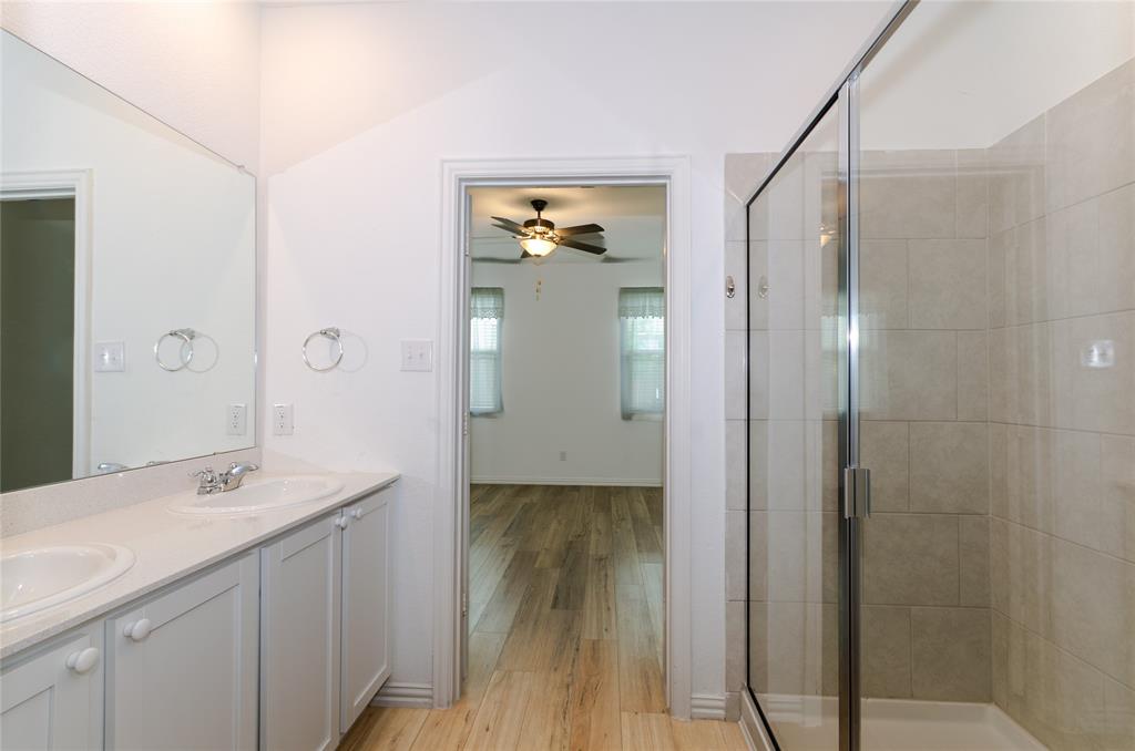 1222 Sequoia Lane Princeton, TX 75407 - Photo 14 of 29 Bathroom featuring wood finished floors, a stall shower, double vanity, a ceiling fan, and baseboards