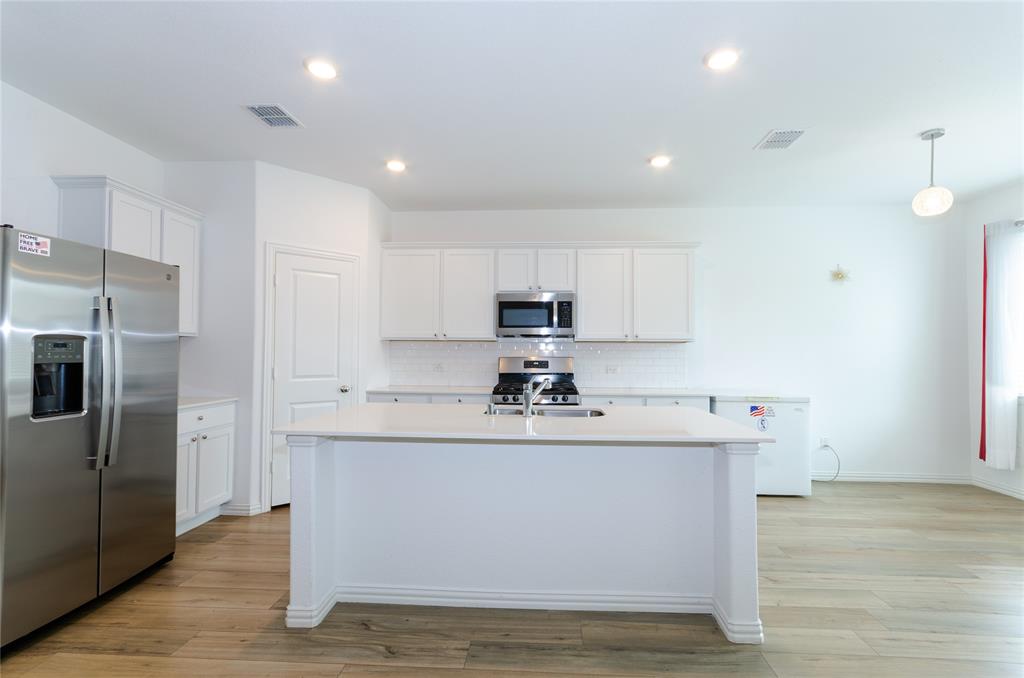 1222 Sequoia Lane Princeton, TX 75407 - Photo 5 of 29 Kitchen featuring stainless steel appliances, light countertops, tasteful backsplash, white cabinets, and a kitchen island with sink