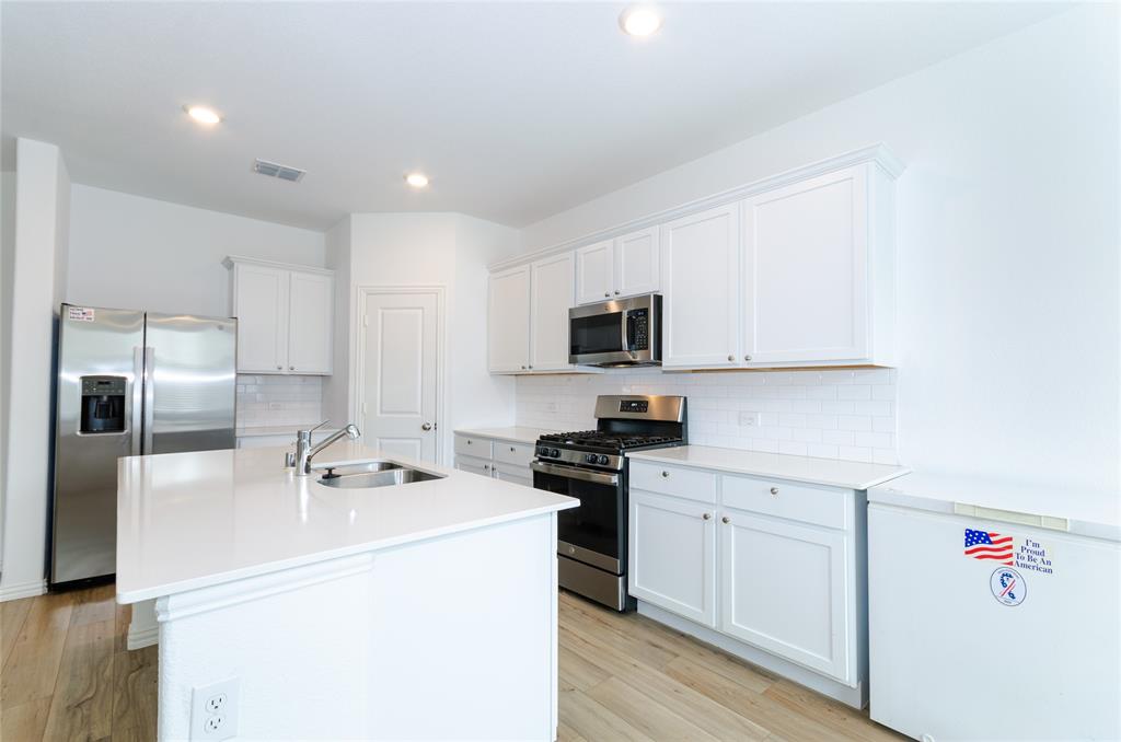 1222 Sequoia Lane Princeton, TX 75407 - Photo 6 of 29 Kitchen featuring stainless steel appliances, a sink, white cabinets, light wood finished floors, and recessed lighting