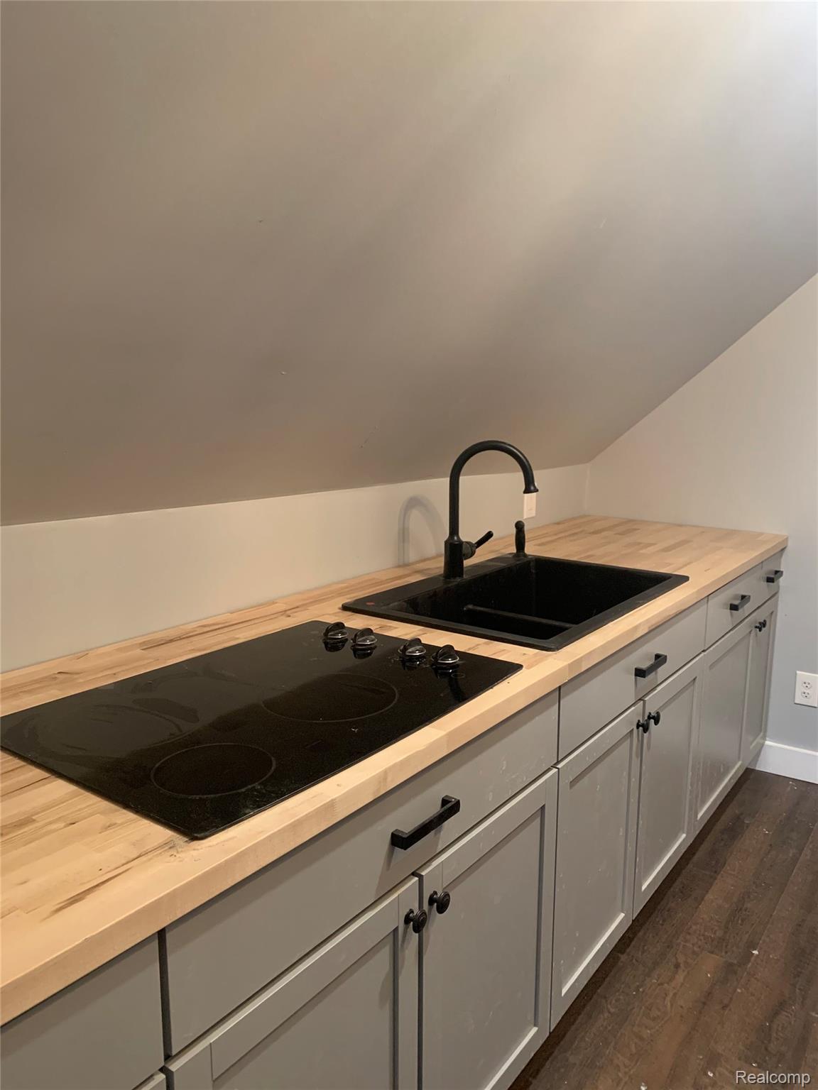 132 Pilgrim Street, Unit STUDIO 3 Highland Park, MI 48203 - Photo 4 of 10 Kitchen with gray cabinets, black electric stovetop, dark wood-type flooring, and wooden counters