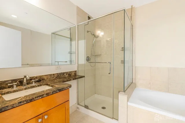 a bathroom with a granite countertop sink a mirror a bathtub and shower