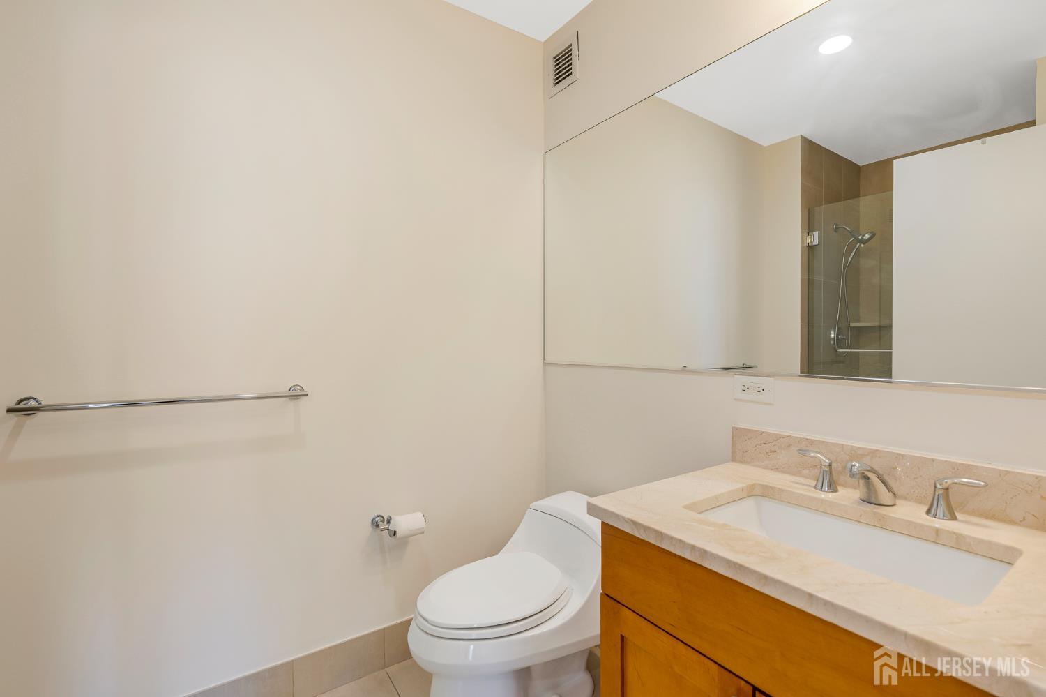1 Spring Street, Unit 1704 New Brunswick, NJ 08901 - Photo 25 of 44 a bathroom with a granite countertop sink toilet and a mirror