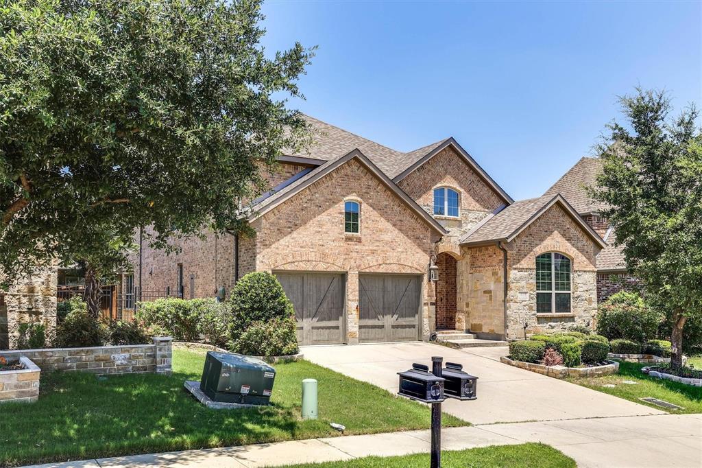 419 Rio Grande Drive Irving, TX 75039 - Photo 2 of 29 Brick and stone facade residence featuring a covered entry porch, arched windows, and two garage doors with a wood-finish design