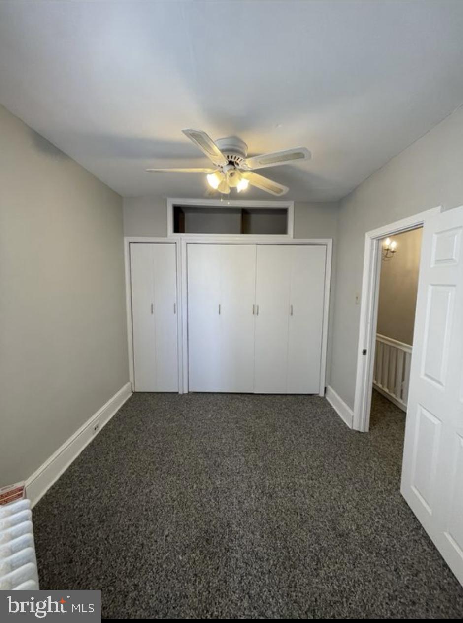5616 Christian Street Philadelphia, PA 19143 - Photo 8 of 12 an empty room with a fireplace and a chandelier fan