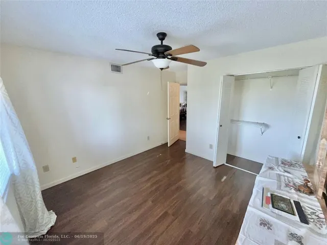 a view of a room with wooden floor and ceiling fan