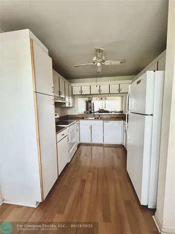 a kitchen with granite countertop a refrigerator a sink and white cabinets