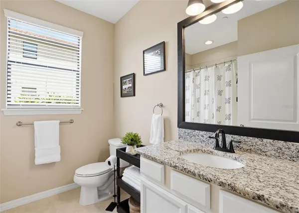 a bathroom with a granite countertop sink and a toilet