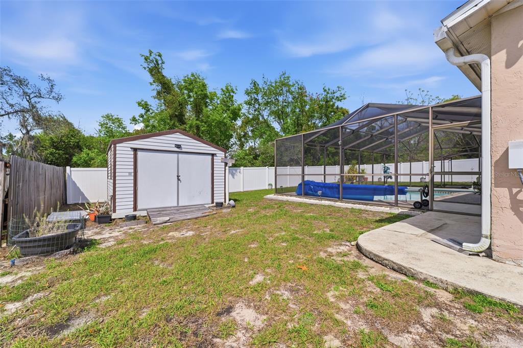 12265 Shafton Road Spring Hill, FL 34608 - Photo 31 of 58 a view of a backyard with a small cabin and a chair