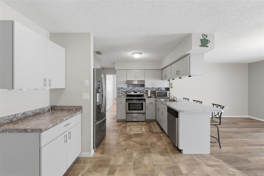 12265 Shafton Road Spring Hill, FL 34608 - Photo 10 of 58 a kitchen with granite countertop a refrigerator and a stove top oven