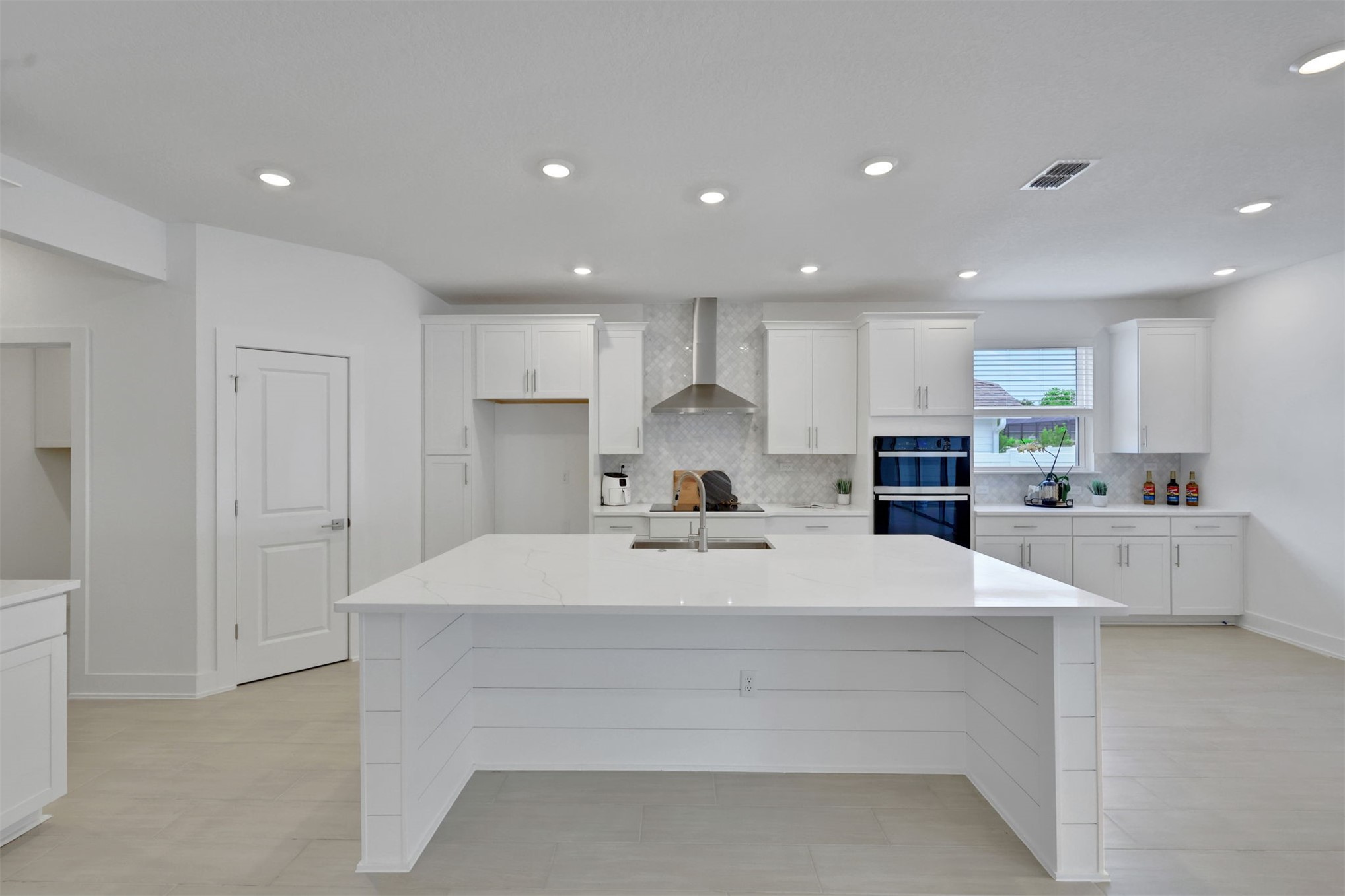 96040 Pirates Bluff Road Yulee, FL 32097 - Photo 18 of 38 a large white kitchen with kitchen island a sink a center island stainless steel appliances and a cabinets