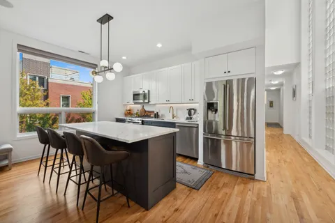 a kitchen with stainless steel appliances a table chairs refrigerator and wooden floor